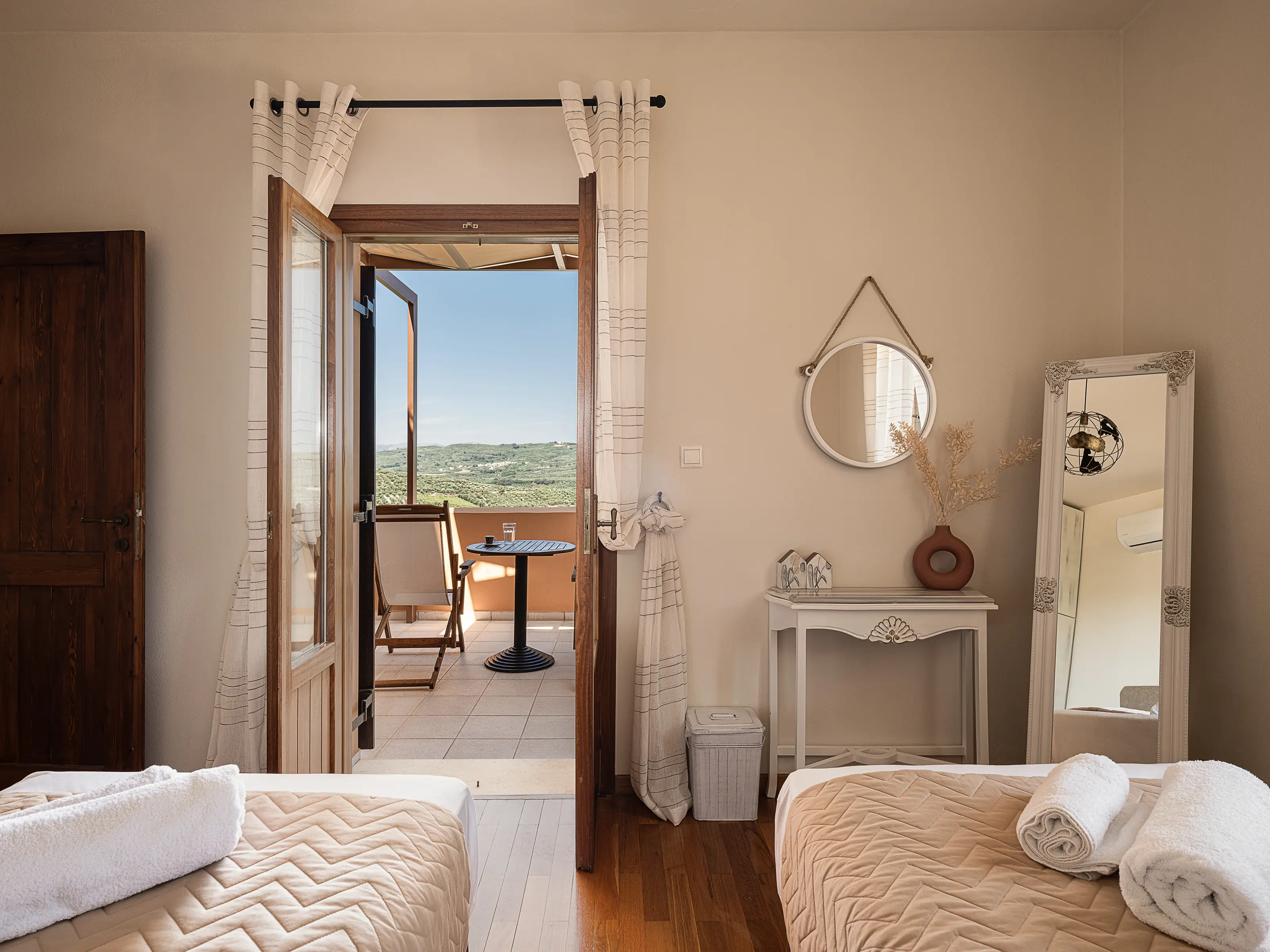 A twin bedroom upstairs, its double doors open onto the balcony and the olive groves beyond